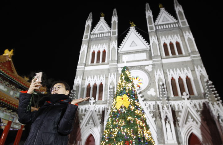 epa07247731 Catholic takes photo beside the Xishiku Catholic Church in Beijing, China, 25 December 2018. Catholics in China attend church masses as they prepare to celebrate the religious holiday to commemorate the birth of Christ.  EPA/WU HONG